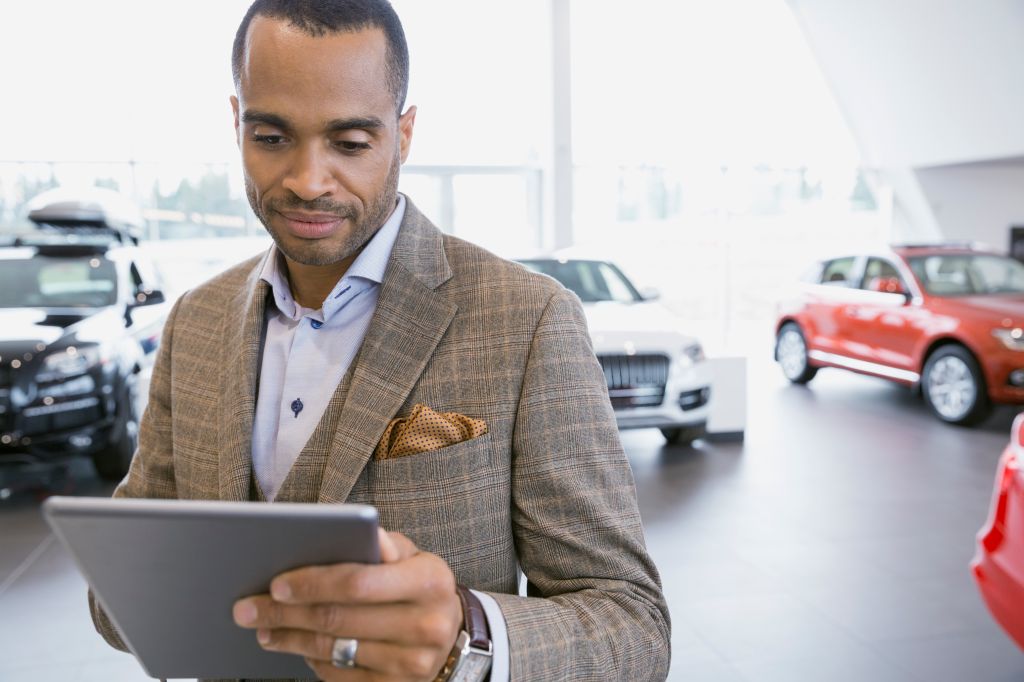 Man using digital tablet in car dealership showroom